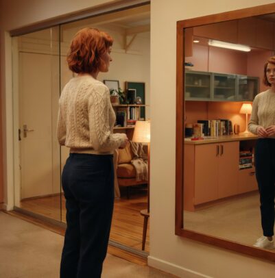 Woman looking at her reflection in a mirror at home
